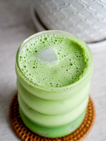 creamy matcha latte showing ice peeking out of the foam on top