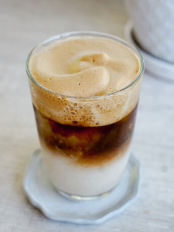 dalgona coffee in a clear glass with coffee foam and white milk layer