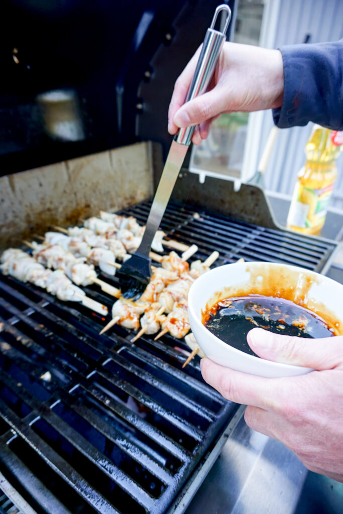 Brushing yakitori sauce onto chicken yakitori skewers