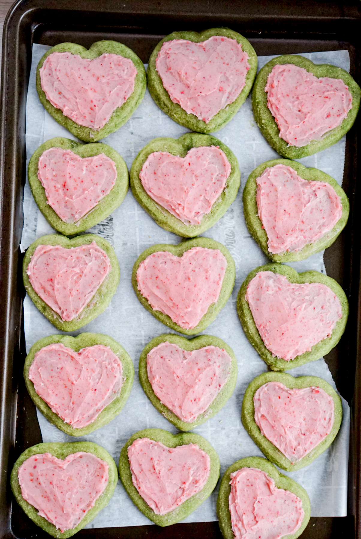 heart shaped matcha almond sugar cookies with strawberry buttercream on top