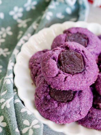 ube thumbprint cookies on a white plate with a green dish towel background