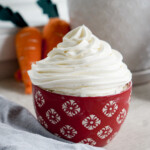 whipped cream cream cheese frosting in a red bowl with piped swirl on top
