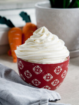 whipped cream cream cheese frosting in a red bowl with piped swirl on top