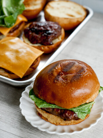 teriyaki burger angled shot with assembled burger and ingredients on a tray in the background