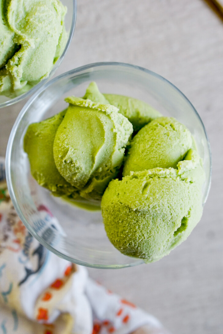 overhead shot of scoops of matcha ice cream in a clear bowl