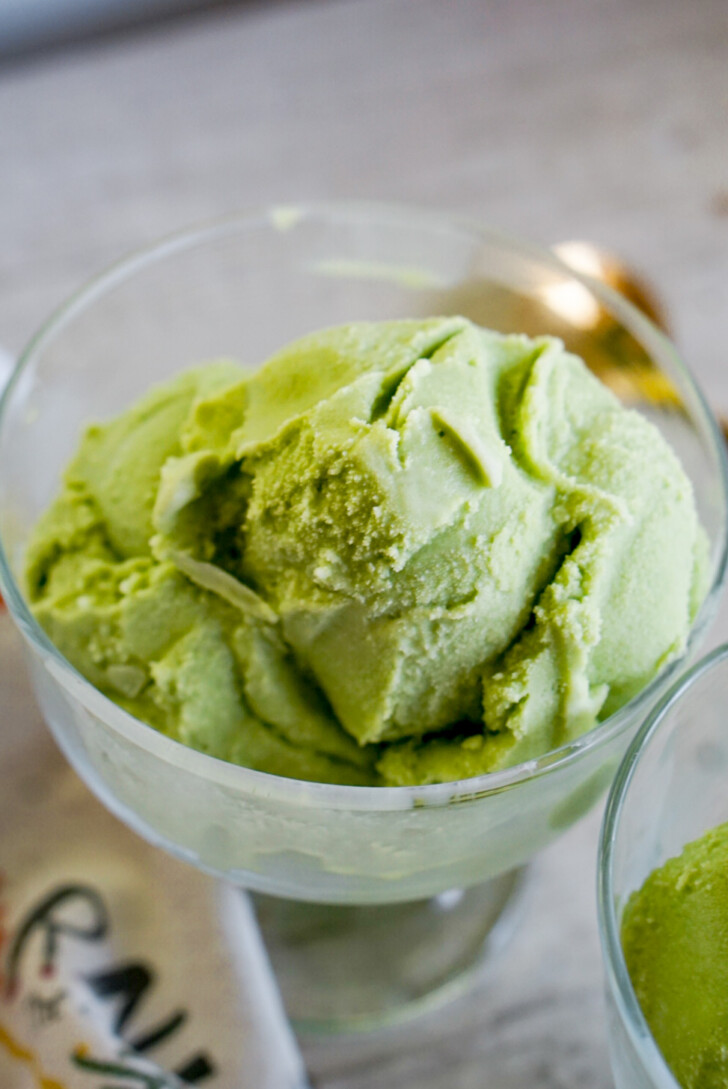 closeup of scoop of green matcha ice cream in clear ice cream bowl