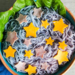 overhead shot of blue and purple tanabata somen in a serving dish with star decorations cut out from cheese and ham