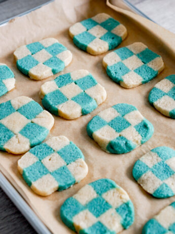 angled shot of blue checkerboard cookies on a baking tray