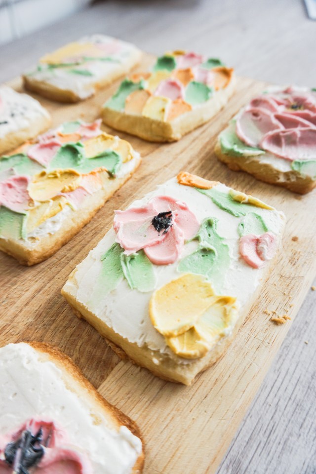 Rectangular cut out shortbread cookies with American buttercream frosting. The buttercream is spatula painted on in an abstract flower design.