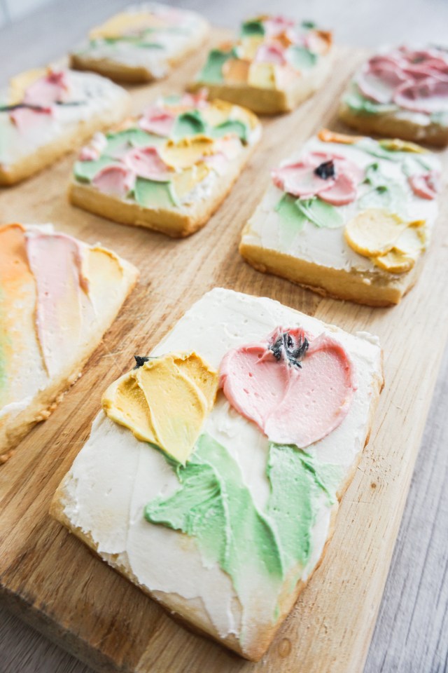Rectangular cut out shortbread cookies with American buttercream frosting. The buttercream is spatula painted on in an abstract flower design.