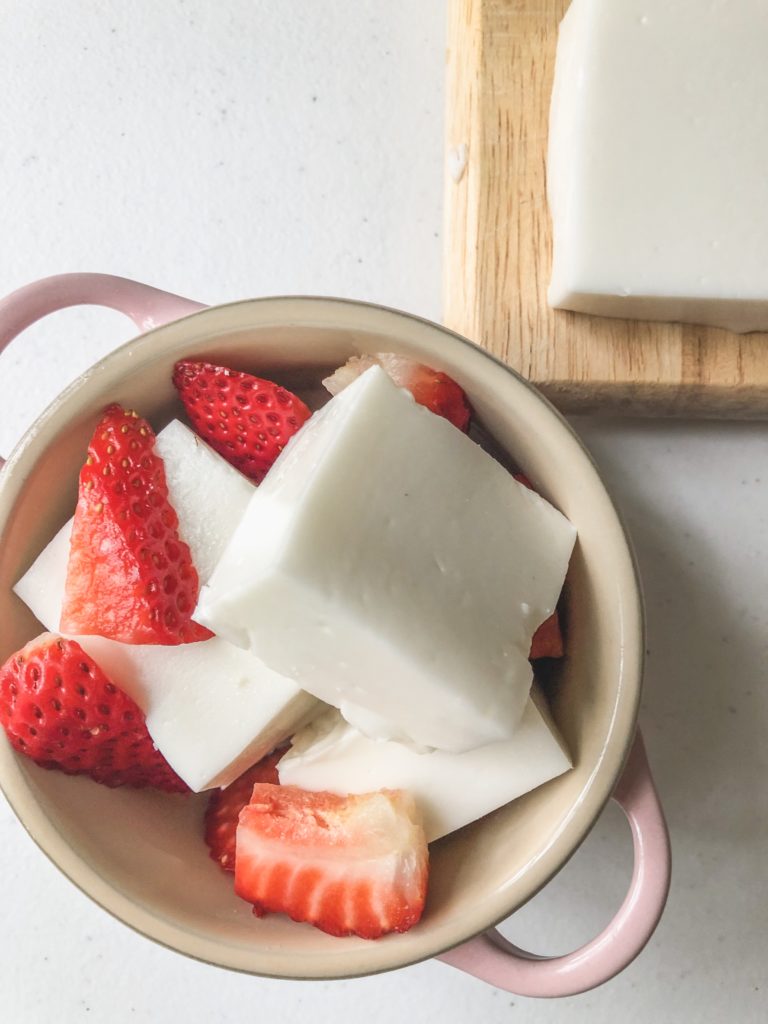 overhead view of haupia squares in a pink le creuset with strawberries