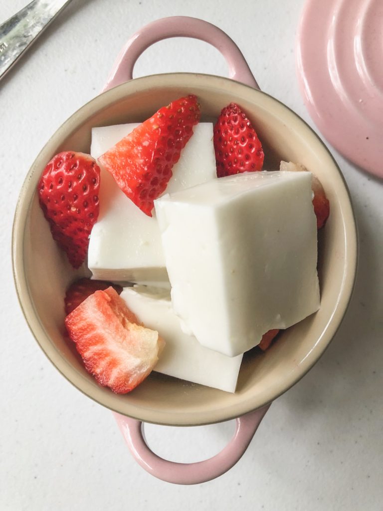 overhead view of haupia squares in a pink le creuset with strawberries