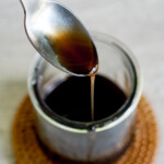 kuromitsu brown sugar syrup being dripped off a spoon into a jar